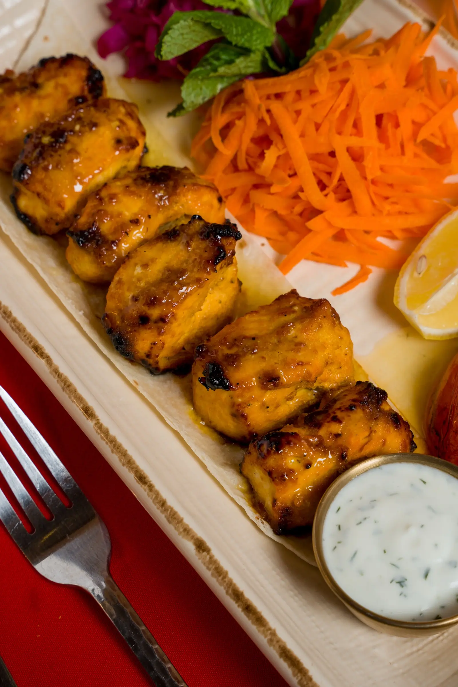 Grilled chicken kabob with yogurt sauce, shredded carrots, and purple cabbage