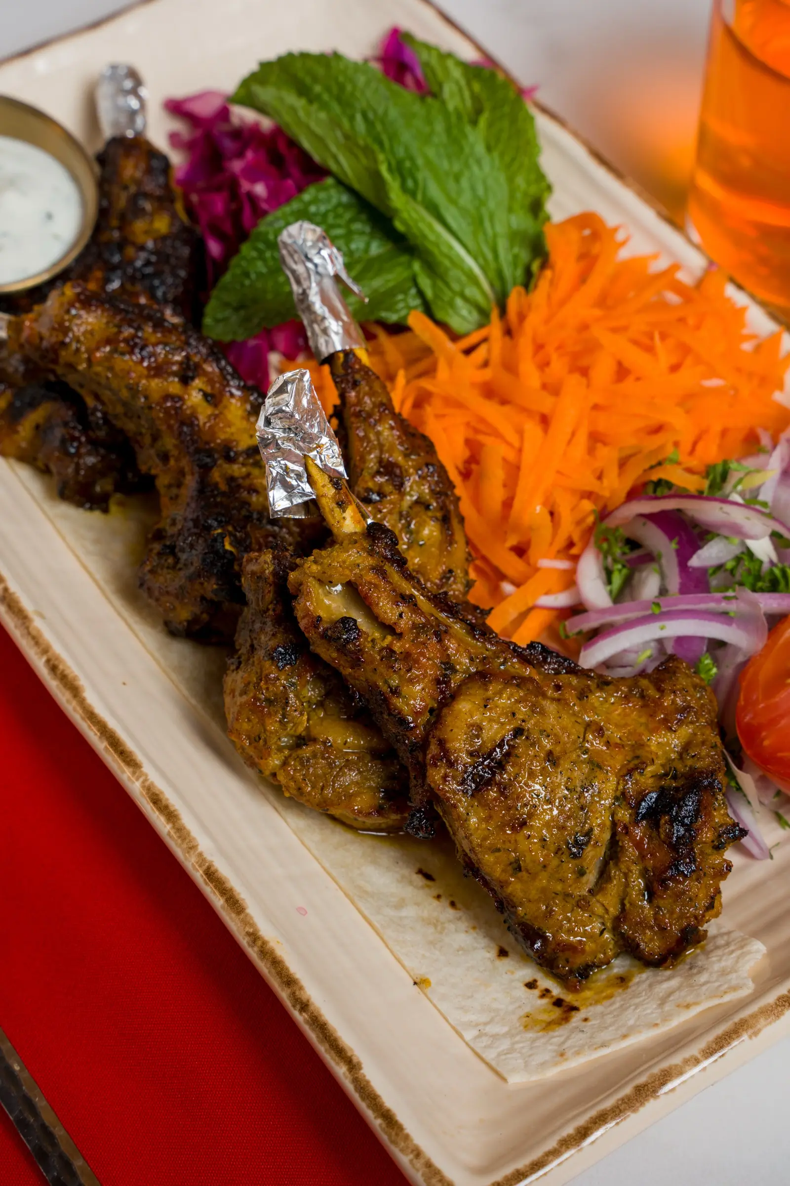 Charred chicken thighs with shredded carrot, pickled red cabbage, and yogurt sauce